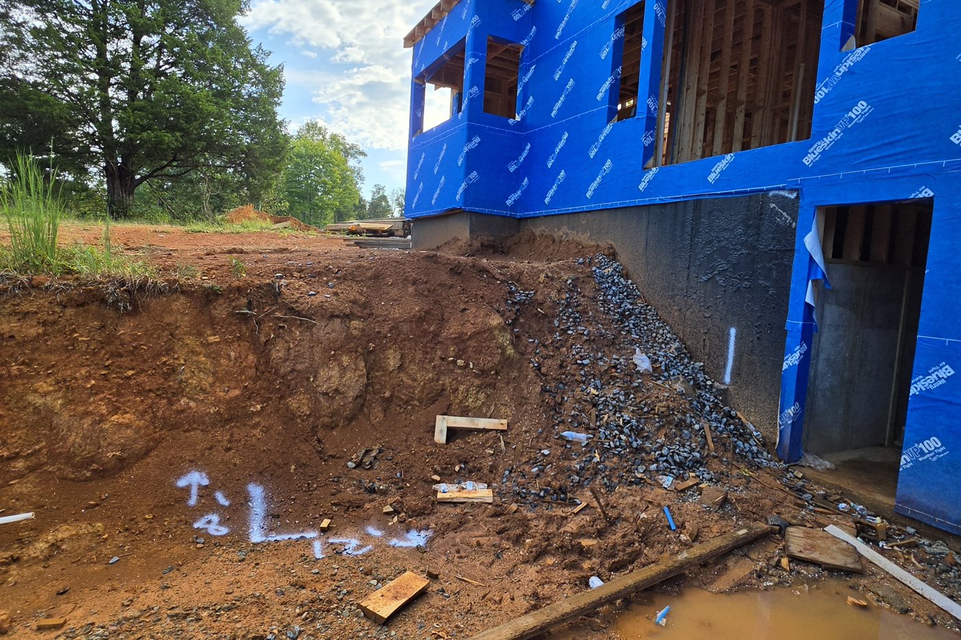 Raw red clay bank cut against a walkout basement door before the retaining wall, Gainesboro TN